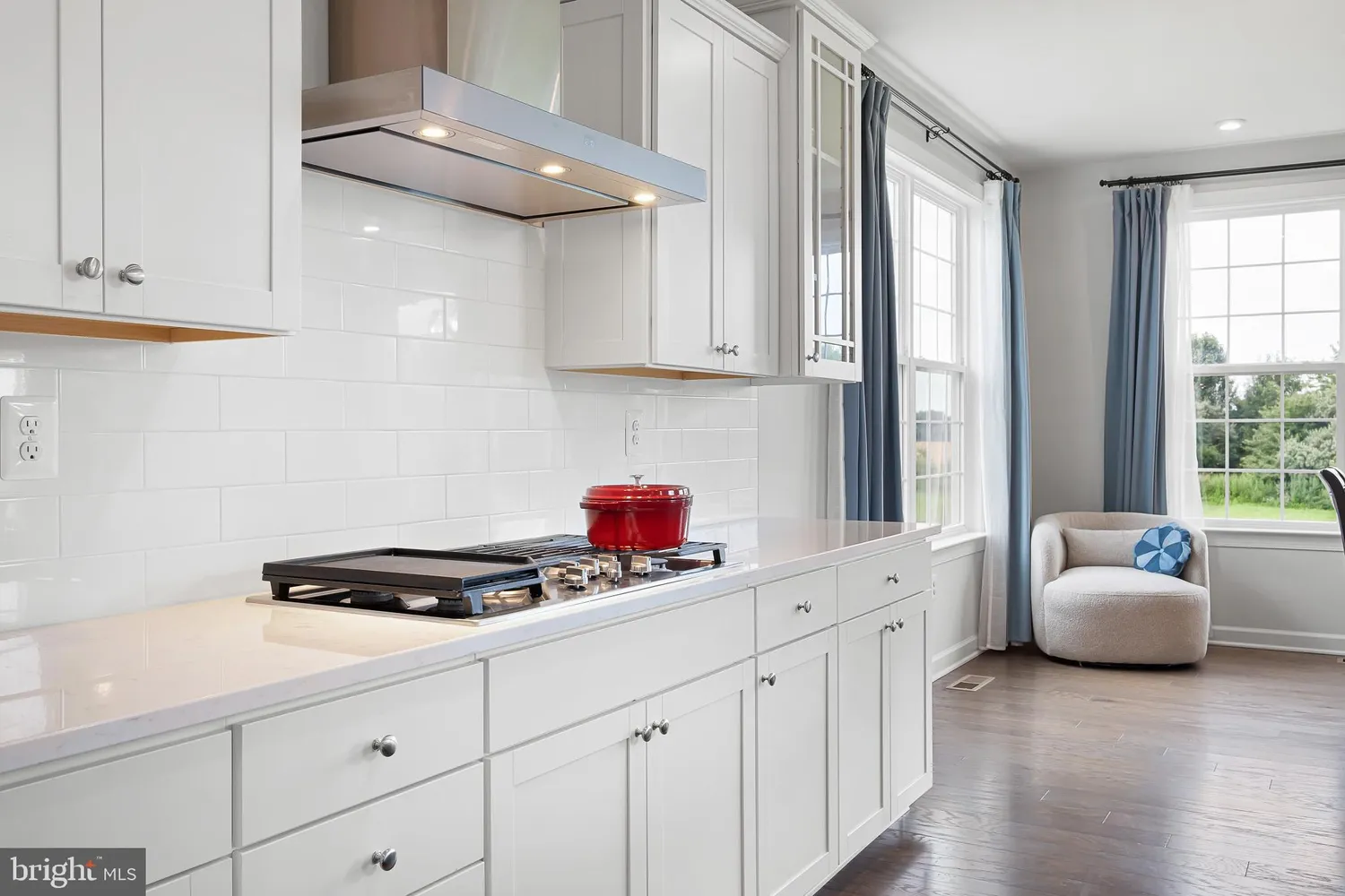 a kitchen with stainless steel appliances a sink dishwasher stove and white cabinets with wooden floor