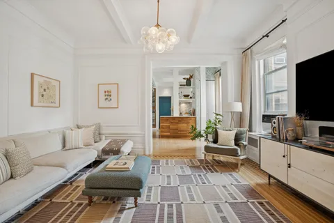 wooden floor with a chandelier and fireplace