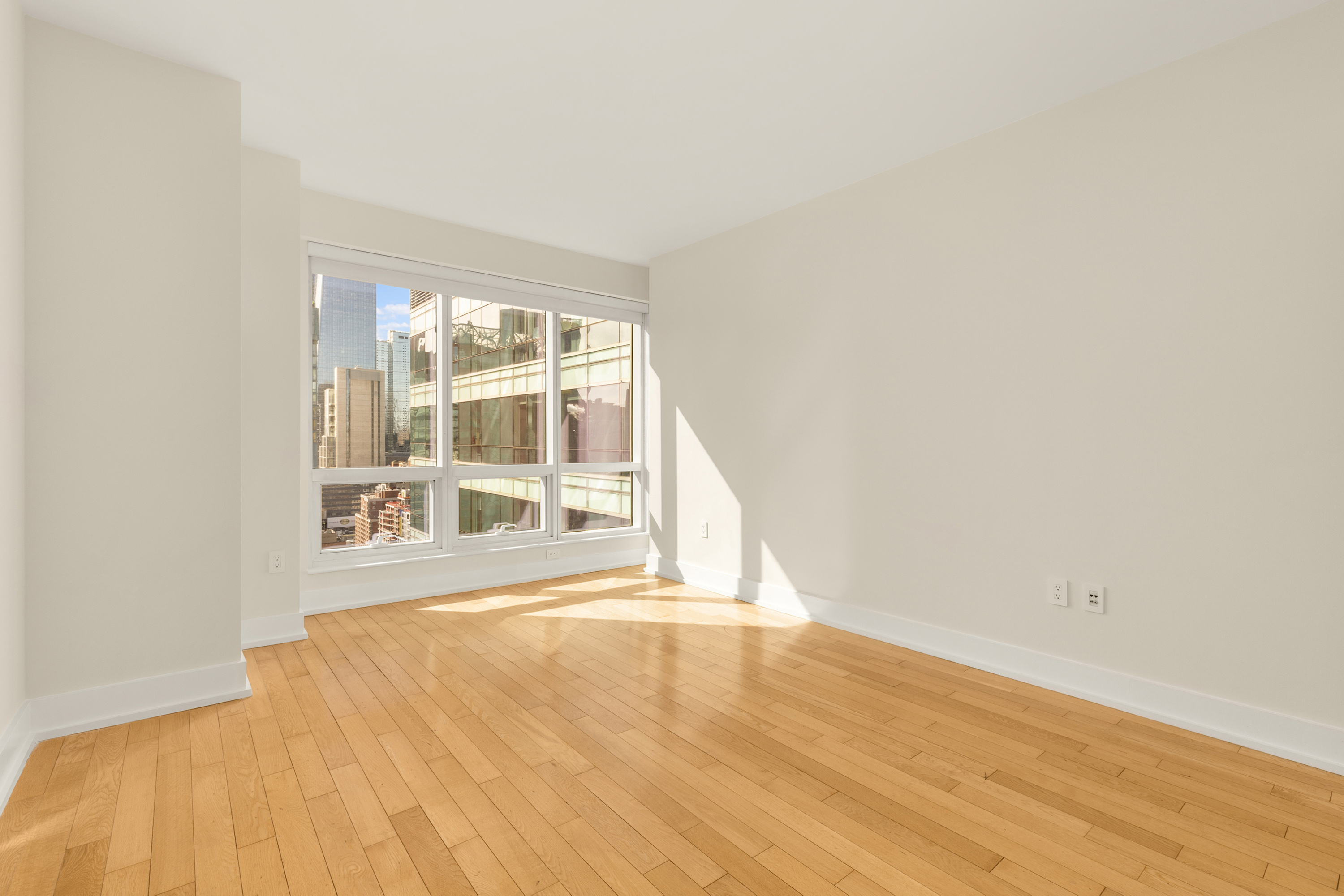 350 West 42nd Street, Unit 26G Manhattan, NY 10036 - Photo 7 of 11 a view of an empty room with wooden floor and a window