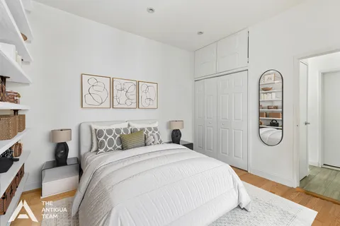 a bedroom with a bed a mirror and paintings on the wall