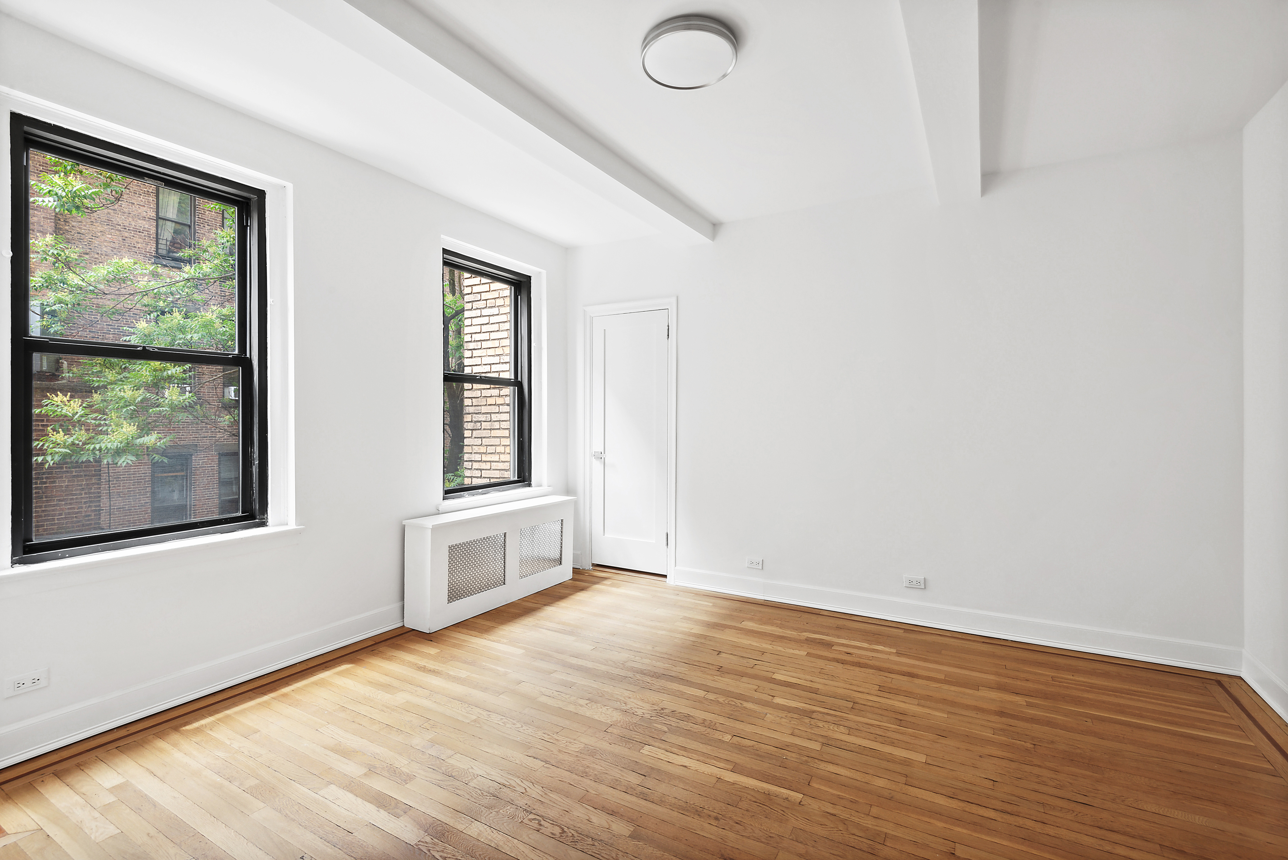 110 West 86th Street, Unit 2D Manhattan, NY 10024 - Photo 2 of 5 an empty room with wooden floor and windows