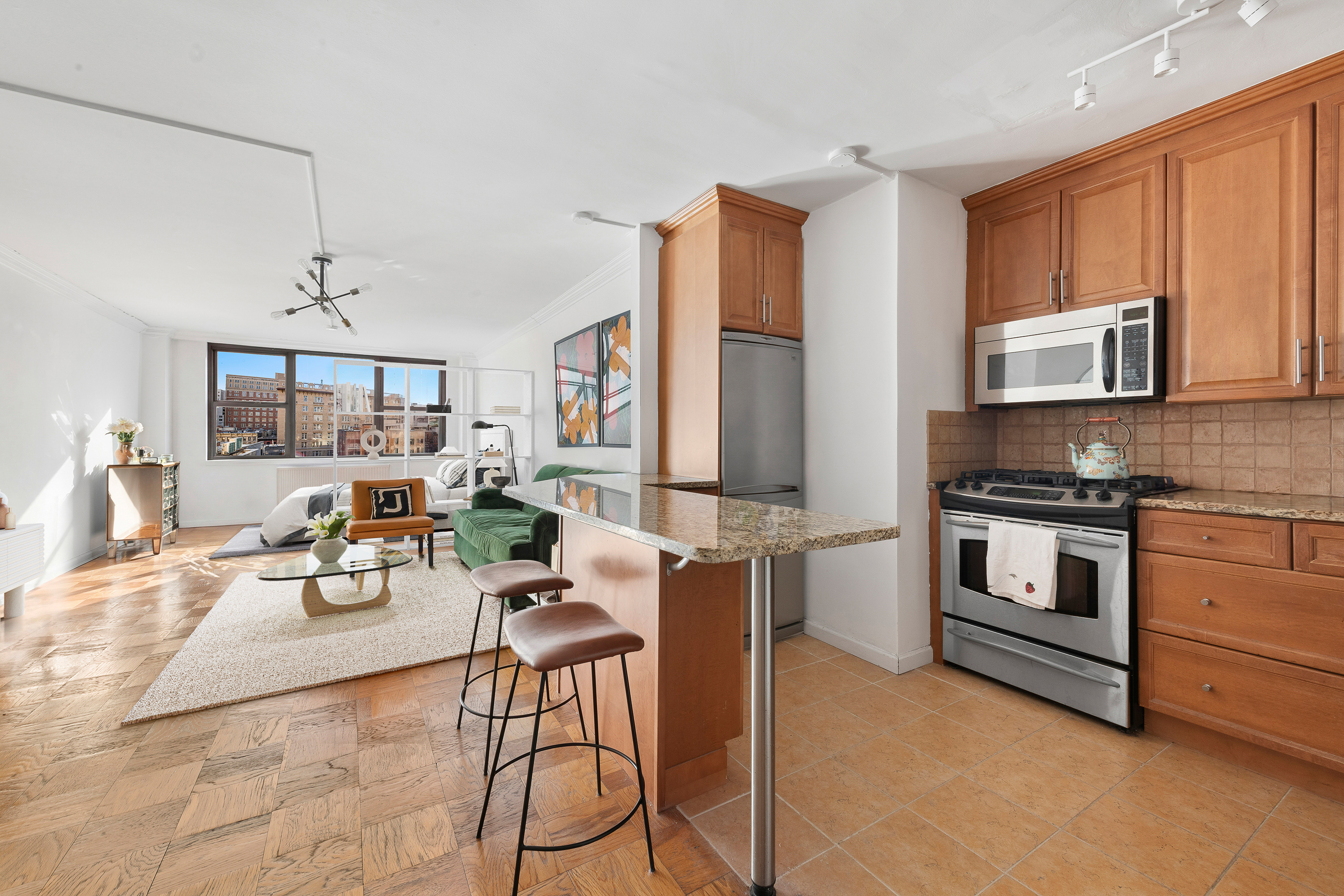 130 East 18th Street, Unit 10M Manhattan, NY 10003 - Photo 4 of 8 a kitchen with stainless steel appliances kitchen island granite countertop a stove a sink and a microwave