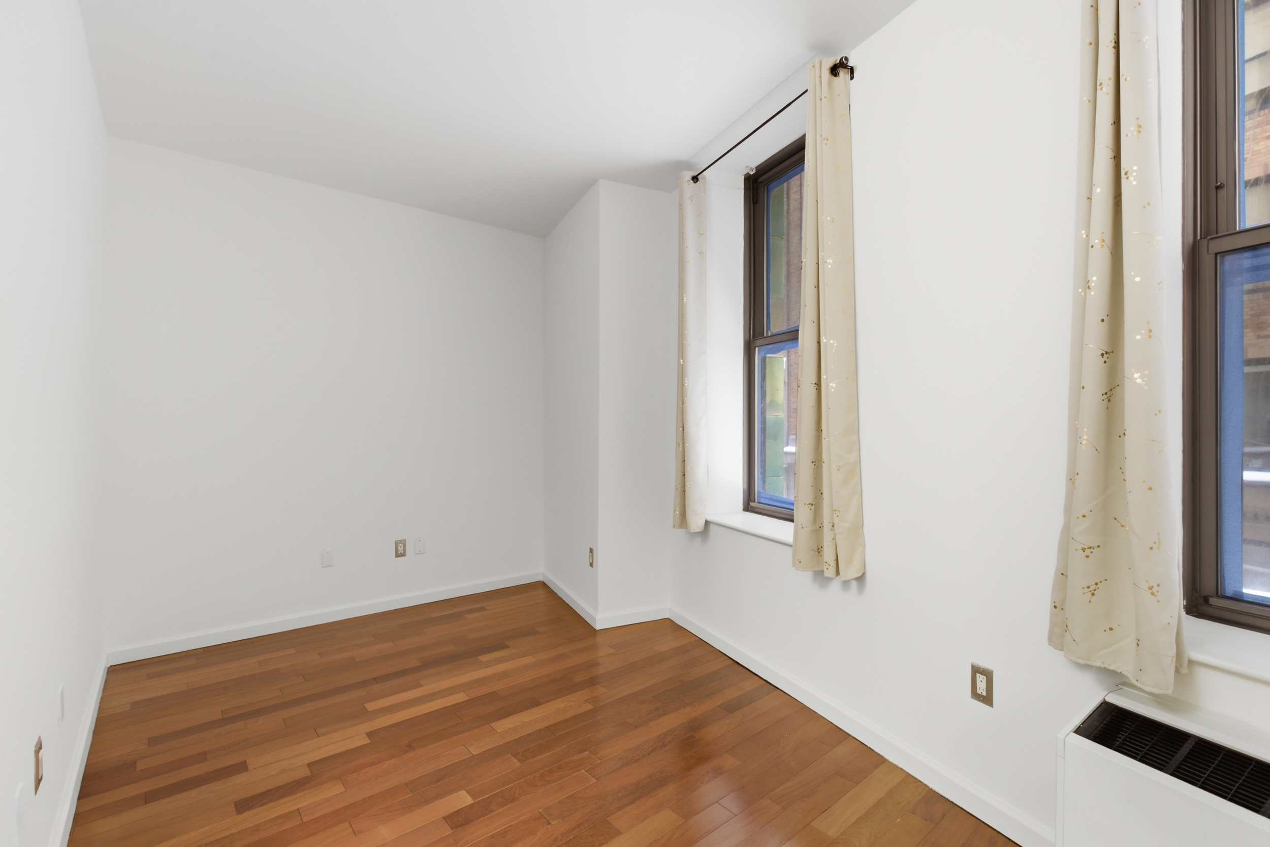 1 Wall Street Court, Unit 406 Manhattan, NY 10005 - Photo 3 of 7 a view of empty room with wooden floor and fan