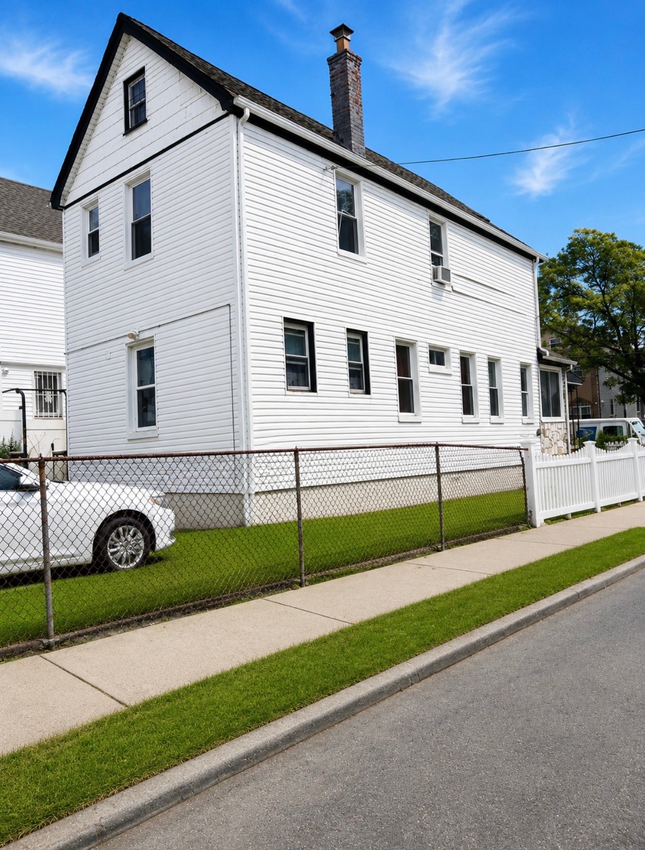 143-01 Ferndale Avenue Queens, NY 11435 - Photo 4 of 5 a view of a white house with a yard and large parking space