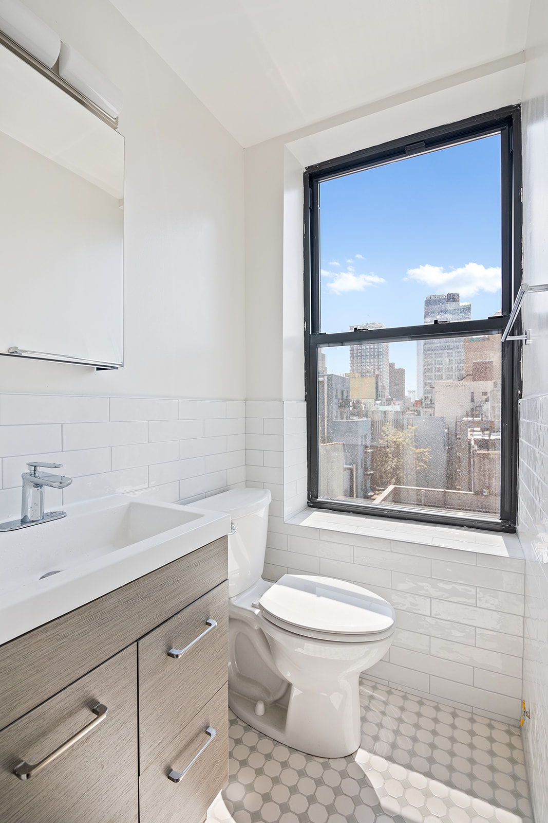 108 Stanton Street, Unit 5D Manhattan, NY 10002 - Photo 5 of 6 a bathroom with a toilet a sink and a large mirror