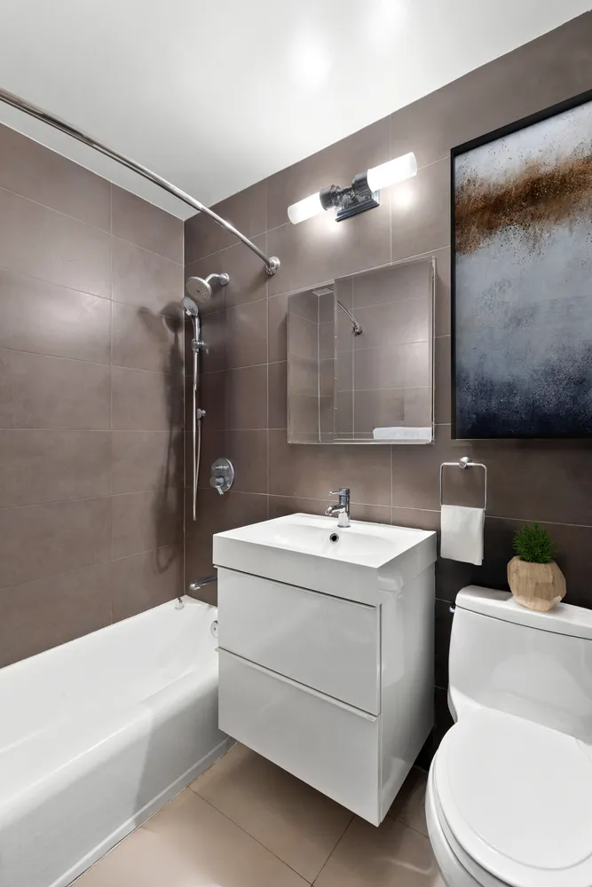 a bathroom with a sink a toilet a mirror and bathtub