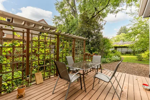 a view of a patio with table and chairs with wooden floor and fence