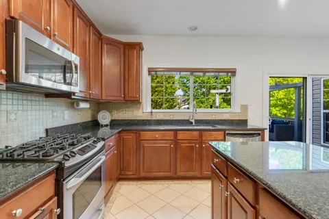 a kitchen with stainless steel appliances granite countertop a stove a sink and a microwave