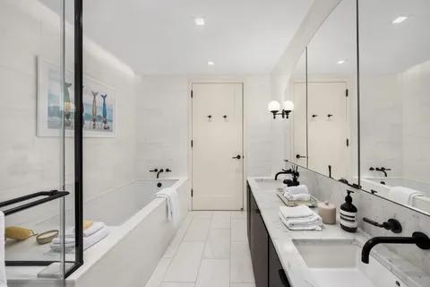 a bathroom with a tub sink shower and mirror