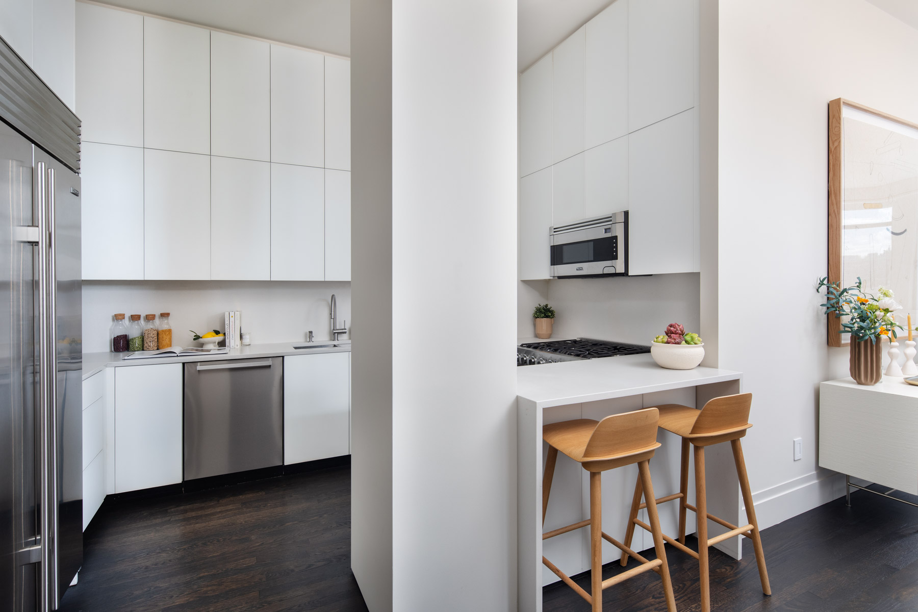252 7th Avenue, Unit 10X Manhattan, NY 10001 - Photo 4 of 20 a kitchen with a stove top oven a sink dishwasher and white cabinets with wooden floor