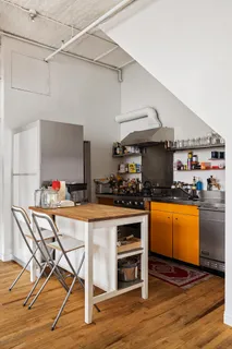 a kitchen with stainless steel appliances kitchen island granite countertop a table chairs in it and wooden floors