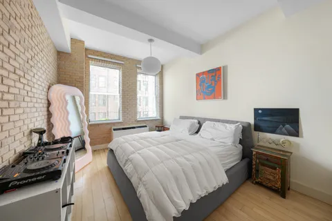 a bedroom with a bed and a flat tv screen on the dresser
