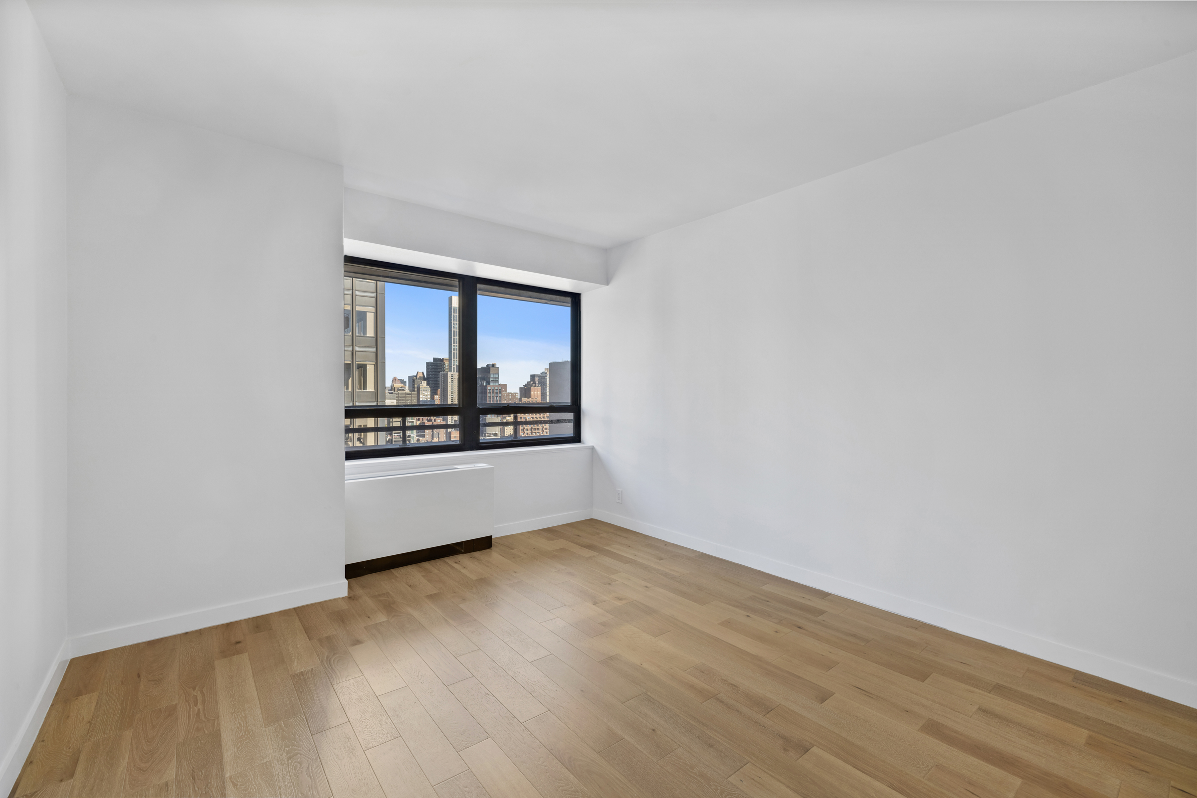 240 East 47th Street, Unit 27C Manhattan, NY 10017 - Photo 6 of 11 a view of an empty room with a window and wooden floor