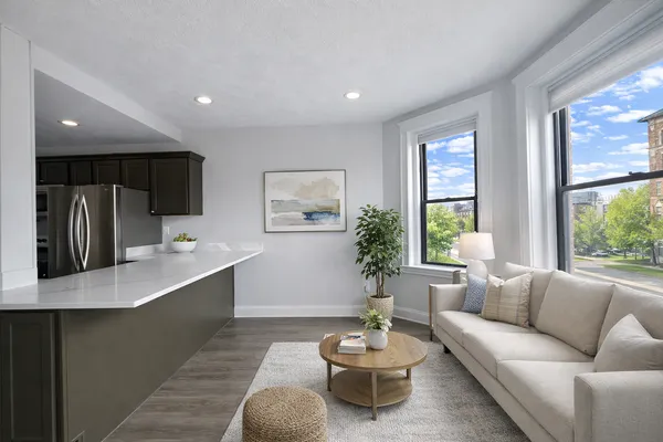 a living room with furniture kitchen view and a large window