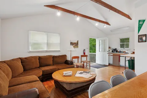a living room with furniture a rug kitchen view and a large window