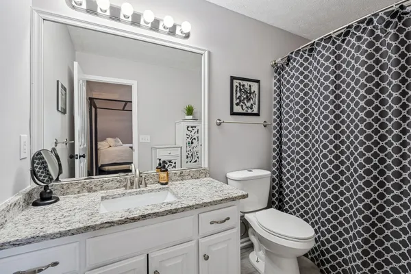 a bathroom with a granite countertop toilet a sink and a mirror