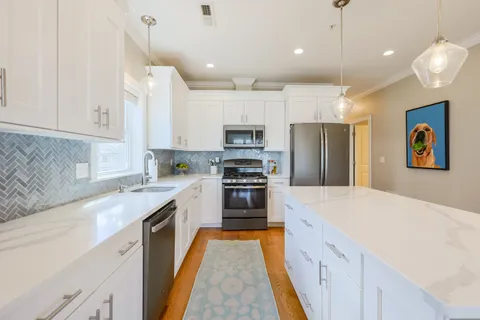 a large kitchen with granite countertop a stove top oven a sink a counter space and cabinets