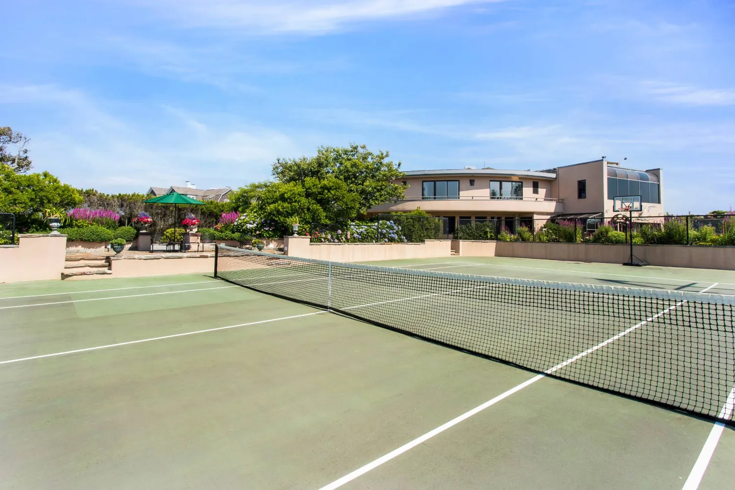 a view of a tennis ground with large trees