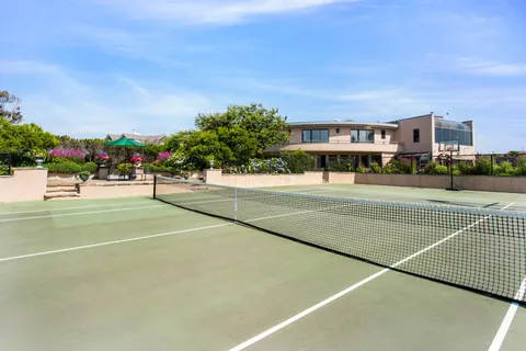 a view of a tennis ground with large trees