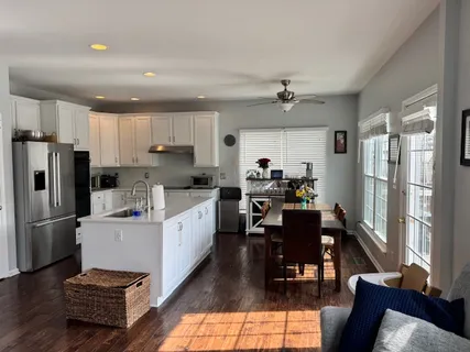 a kitchen with stainless steel appliances a refrigerator a stove a sink dishwasher a dining table and chairs with wooden floor