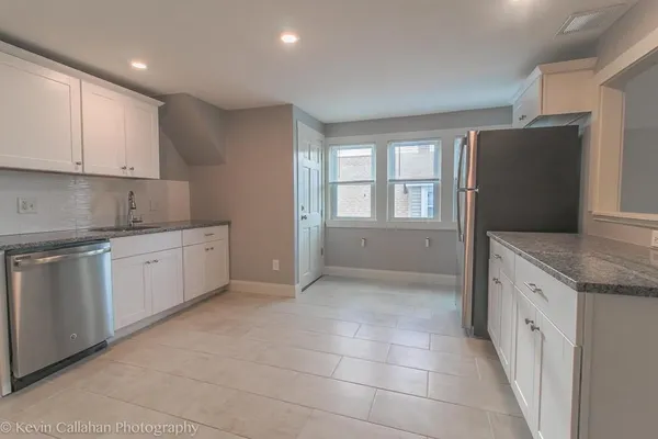 a kitchen with granite countertop white cabinets and white appliances