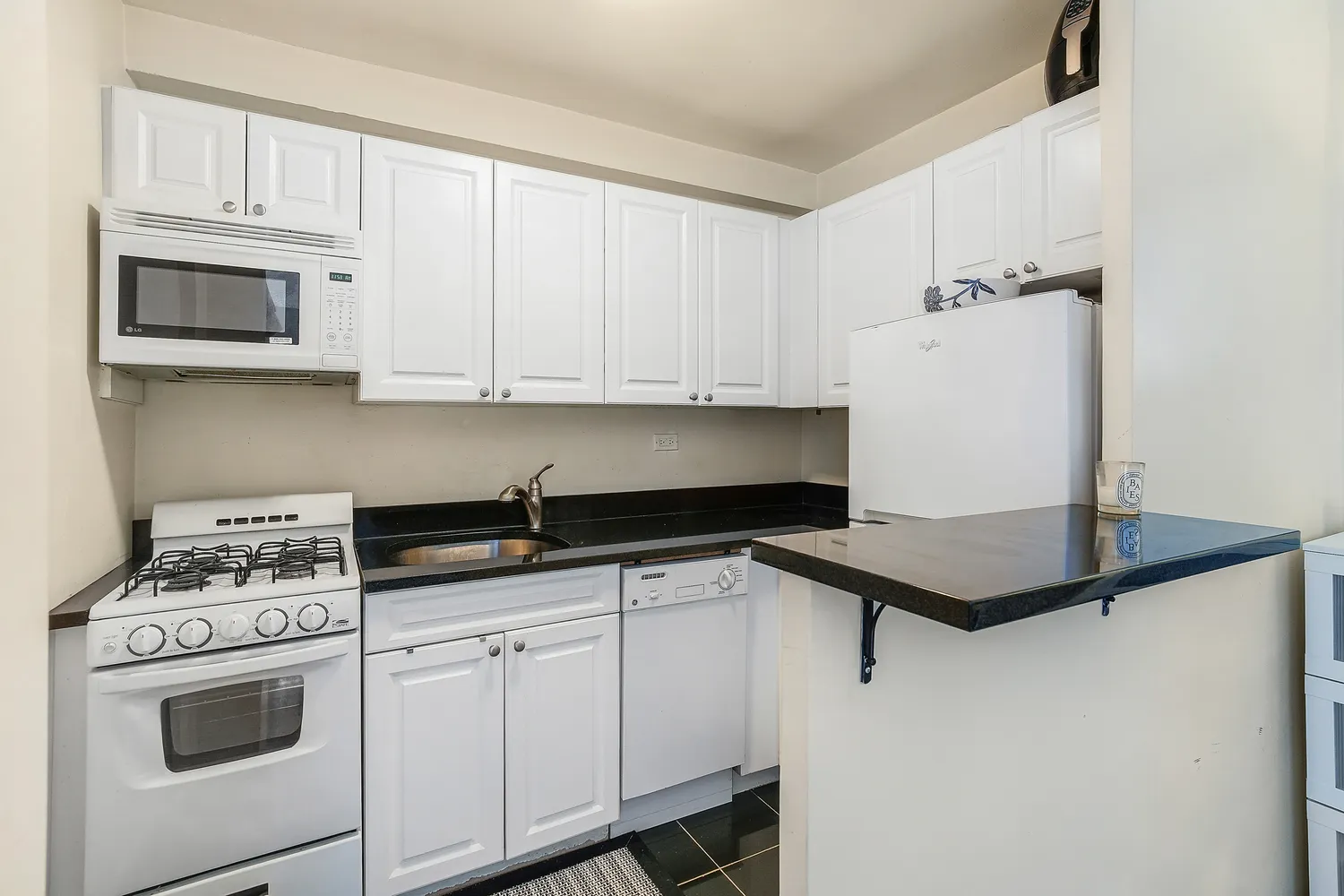 a kitchen with granite countertop white cabinets and white appliances