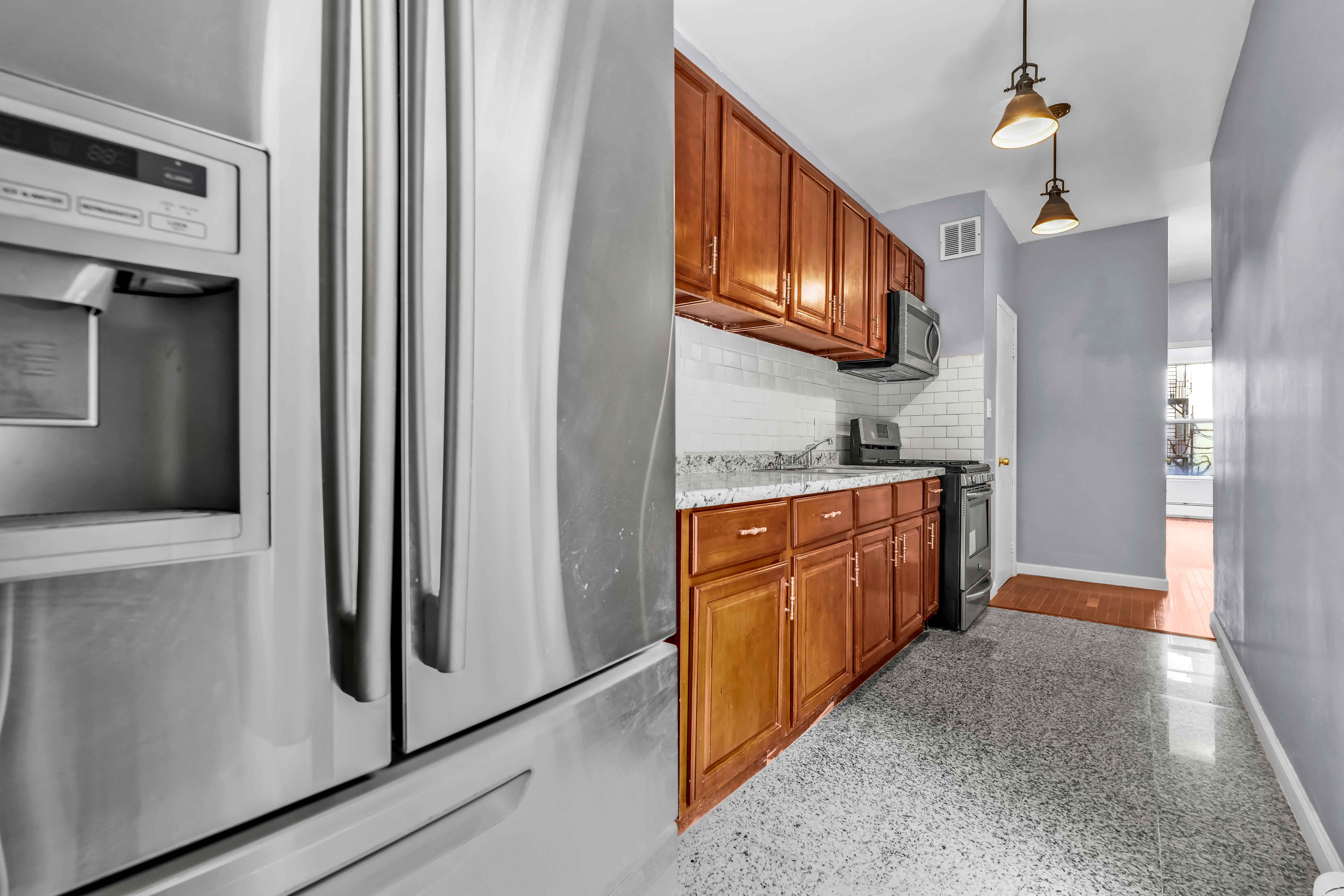 1633 St Johns Place, Unit 3 Brooklyn, NY 11233 - Photo 21 of 29 a kitchen with stainless steel appliances granite countertop a refrigerator a stove top oven a sink dishwasher and wooden cabinets