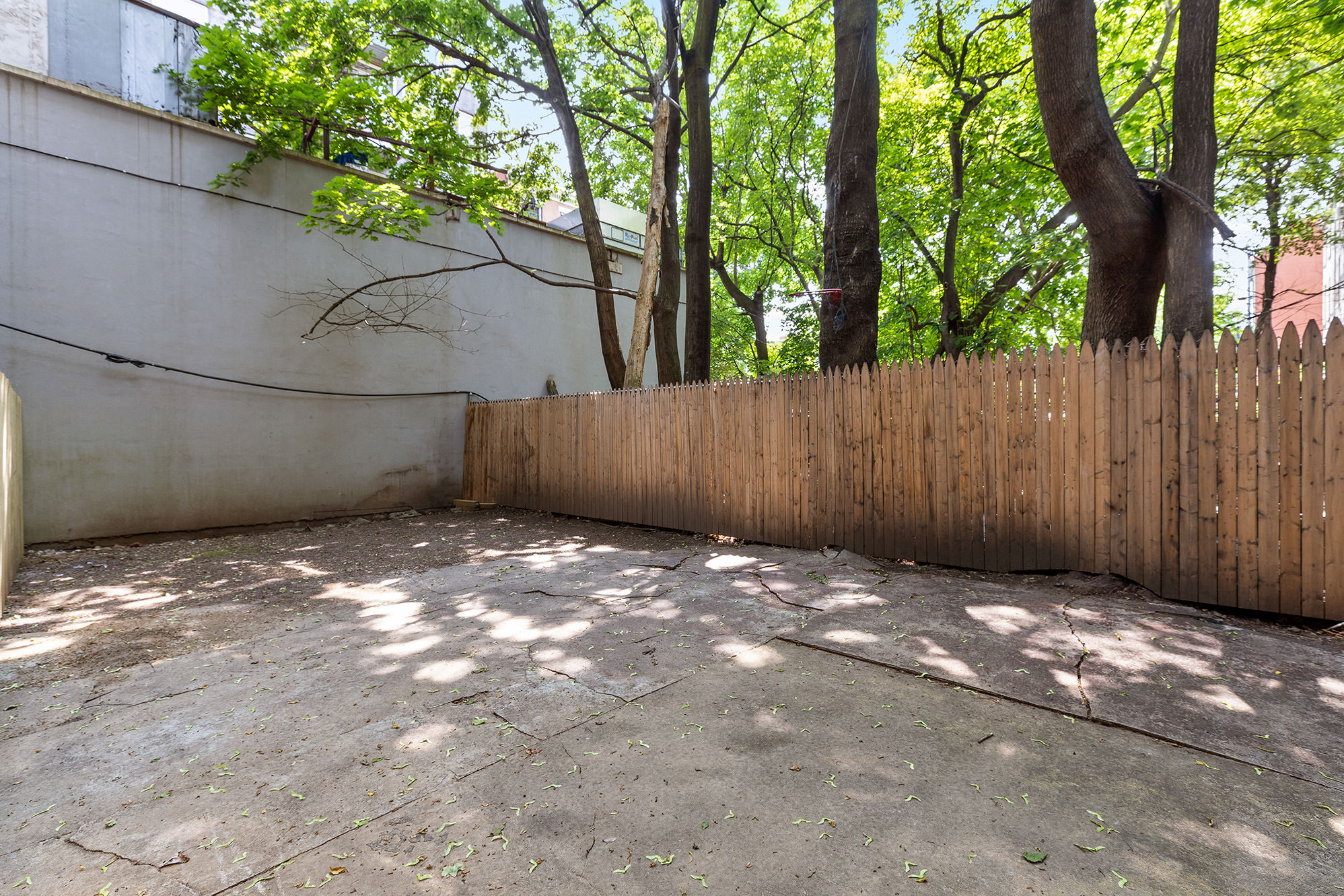 306 Gates Avenue, Unit 1A Brooklyn, NY 11216 - Photo 9 of 14 a backyard of a house with large trees and wooden fence