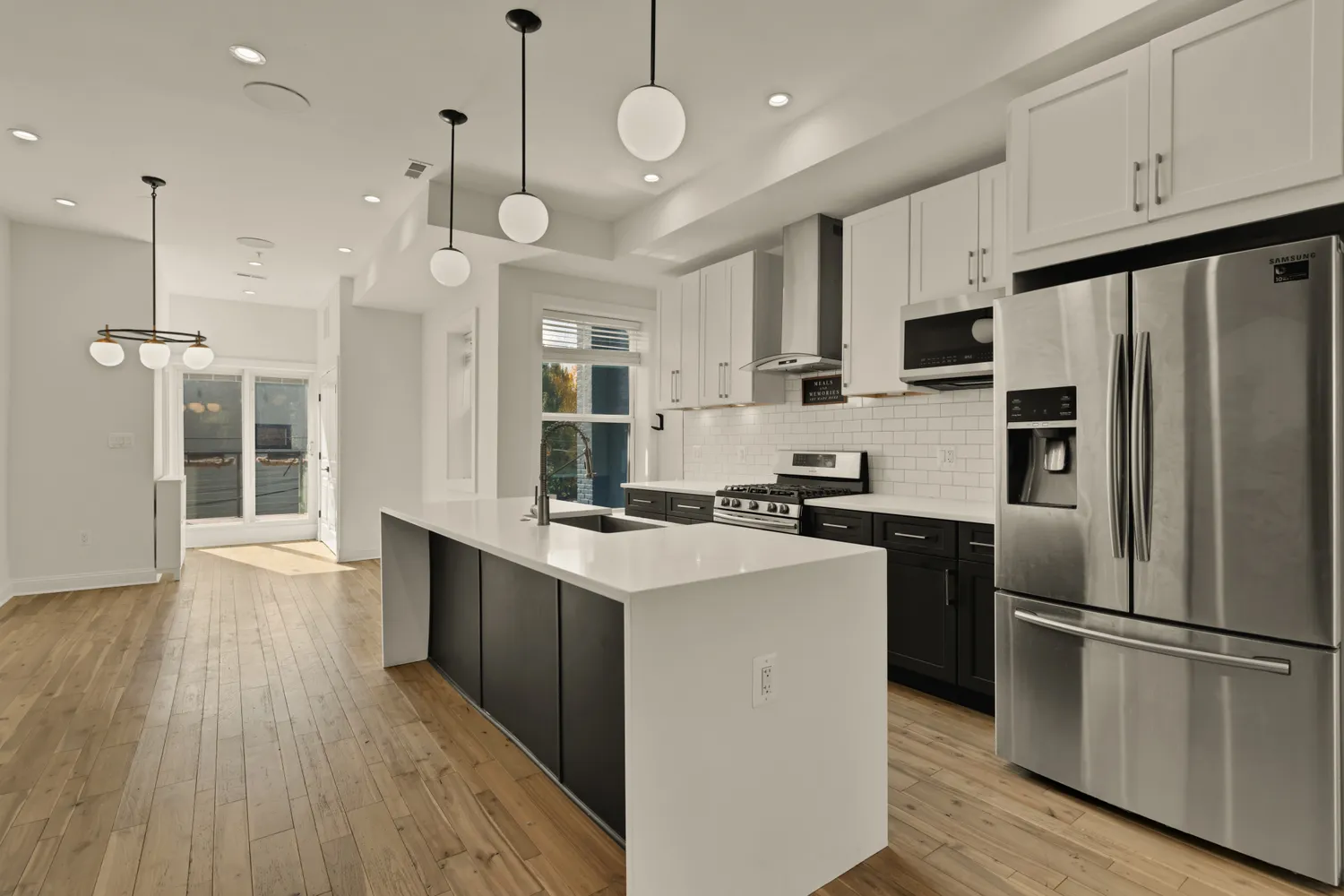 a kitchen with stainless steel appliances a stove a refrigerator a sink and white cabinets with wooden floor