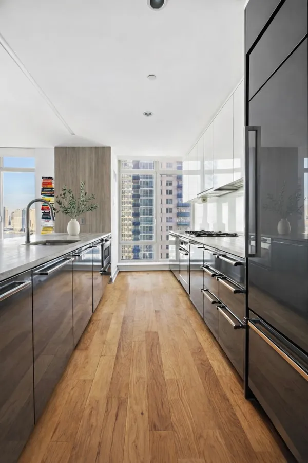 a large kitchen with kitchen island granite countertop a large window and stainless steel appliances