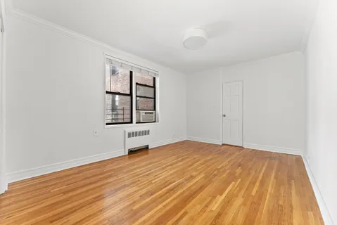 a view of an empty room with window and wooden floor