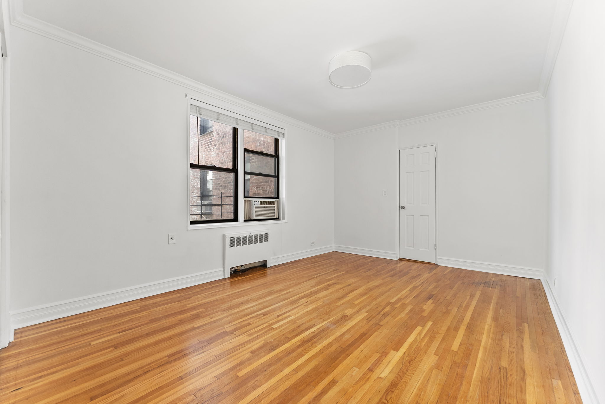 675 Academy Street, Unit 3A Manhattan, NY 10034 - Photo 8 of 12 a view of an empty room with window and wooden floor