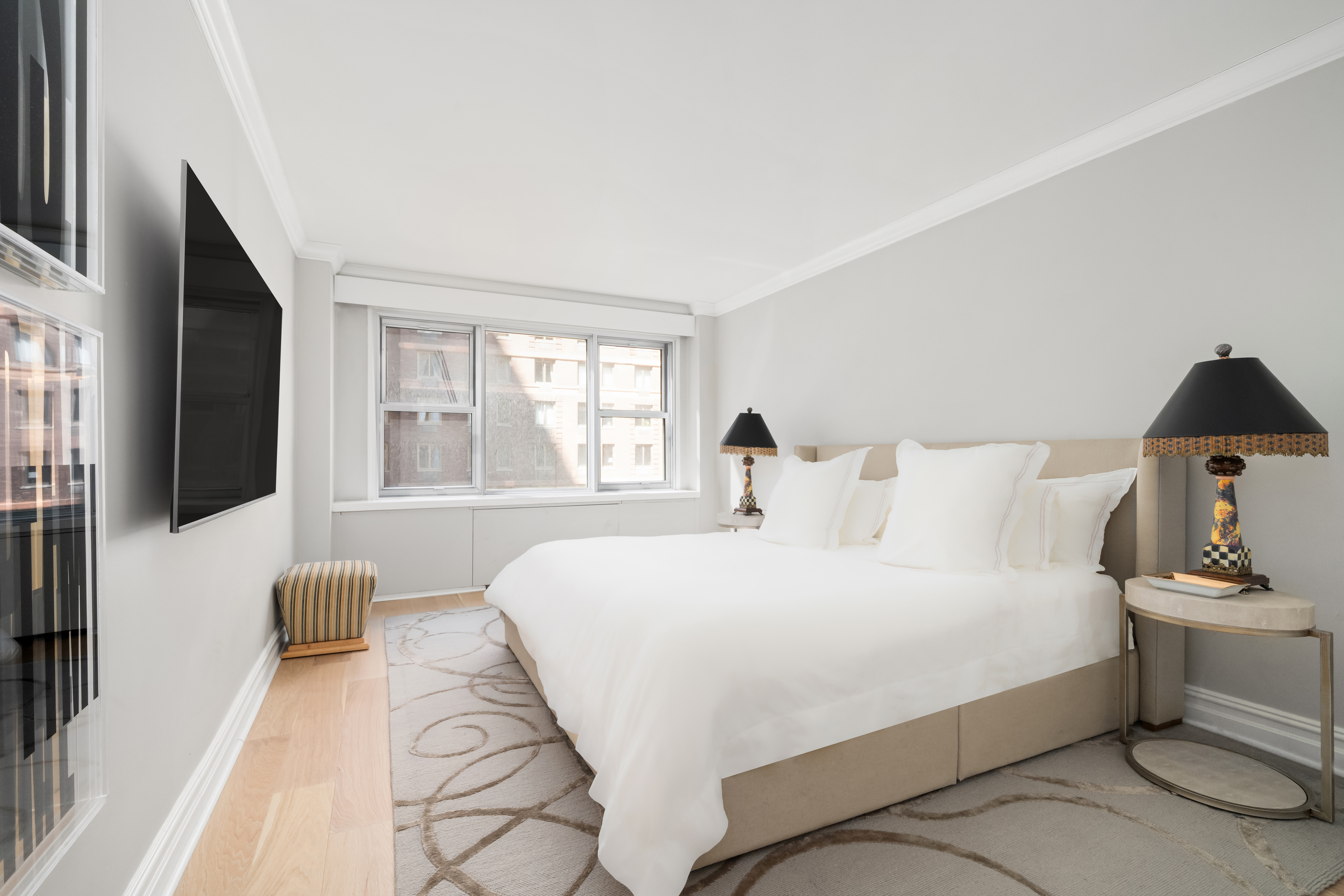 77 West 55th Street, Unit 9F Manhattan, NY 10019 - Photo 9 of 11 a bedroom with a large bed and a flat tv screen on dresser