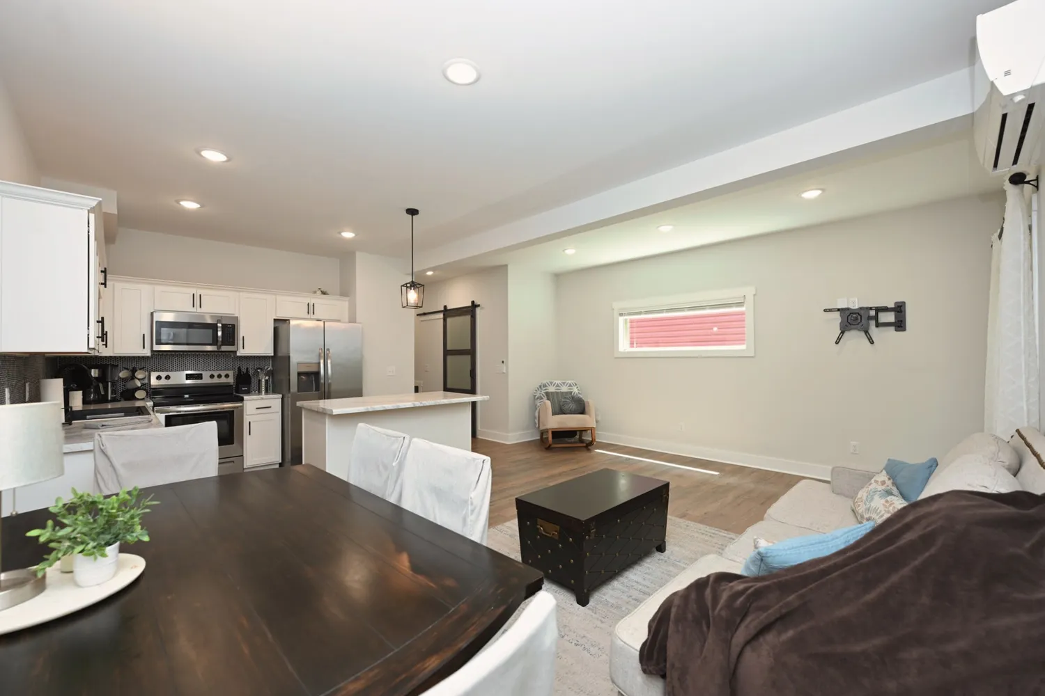 a living room with couches and kitchen view with wooden floor