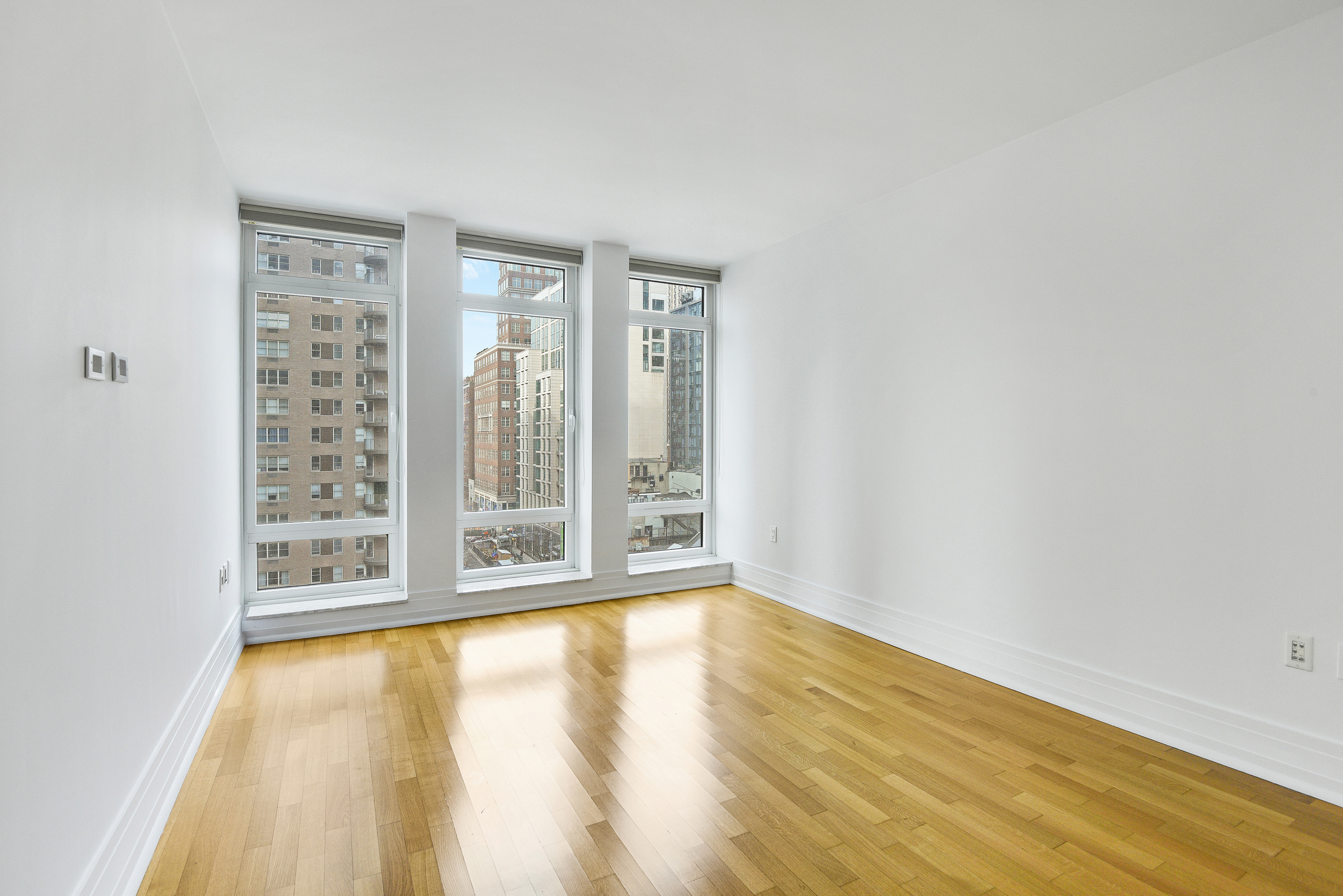 205 East 85th Street, Unit 12H Manhattan, NY 10028 - Photo 12 of 19 a view of an empty room with wooden floor and a window