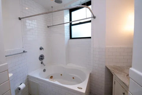 a bathroom with a bathtub a window and a shower