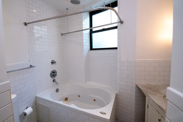 a bathroom with a bathtub a window and a shower