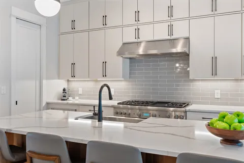 a kitchen with stainless steel appliances a sink a stove and white cabinets