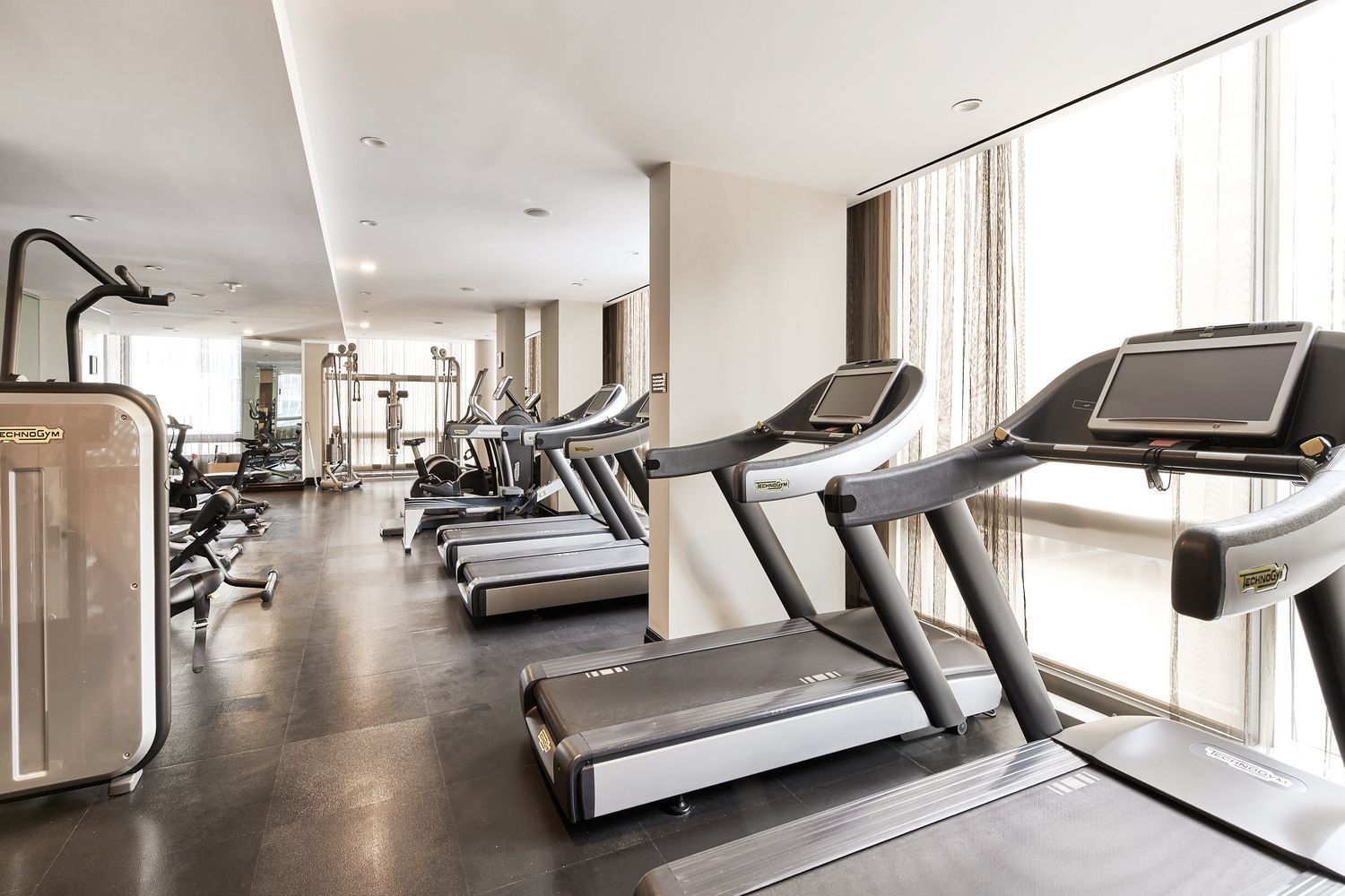 246 Spring Street, Unit 4105 Manhattan, NY 10013 - Photo 7 of 13 a view of gym equipment and living room with windows