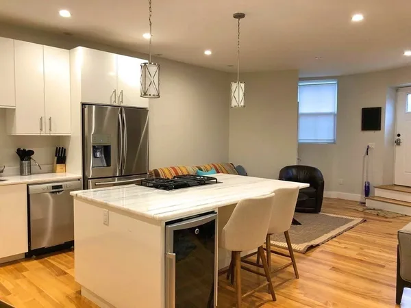 a kitchen with stainless steel appliances kitchen island granite countertop a sink a stove a refrigerator and island with wooden floor
