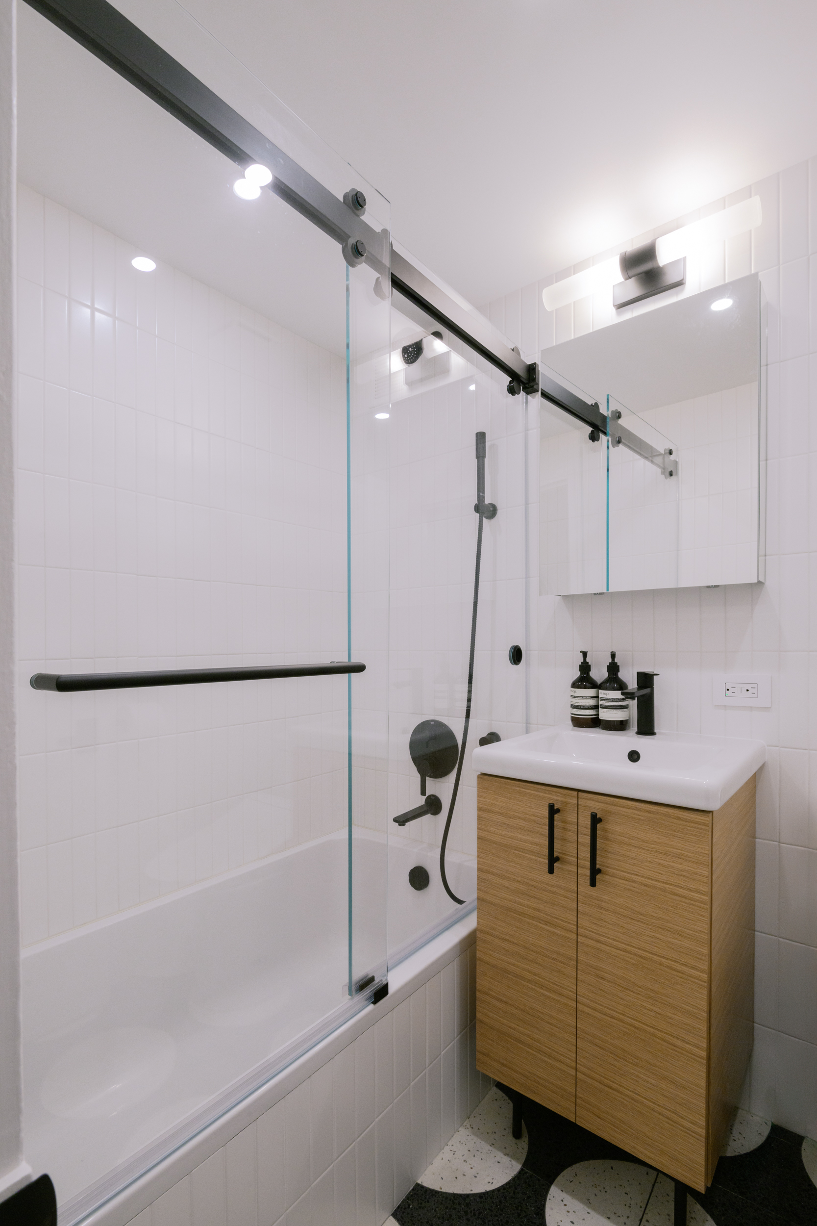 211 Thompson Street, Unit 4J Manhattan, NY 10012 - Photo 4 of 8 a bathroom with a sink a mirror and a shower