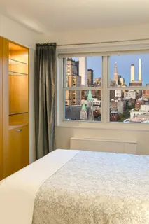 a bedroom with a bed and a dresser next to a window