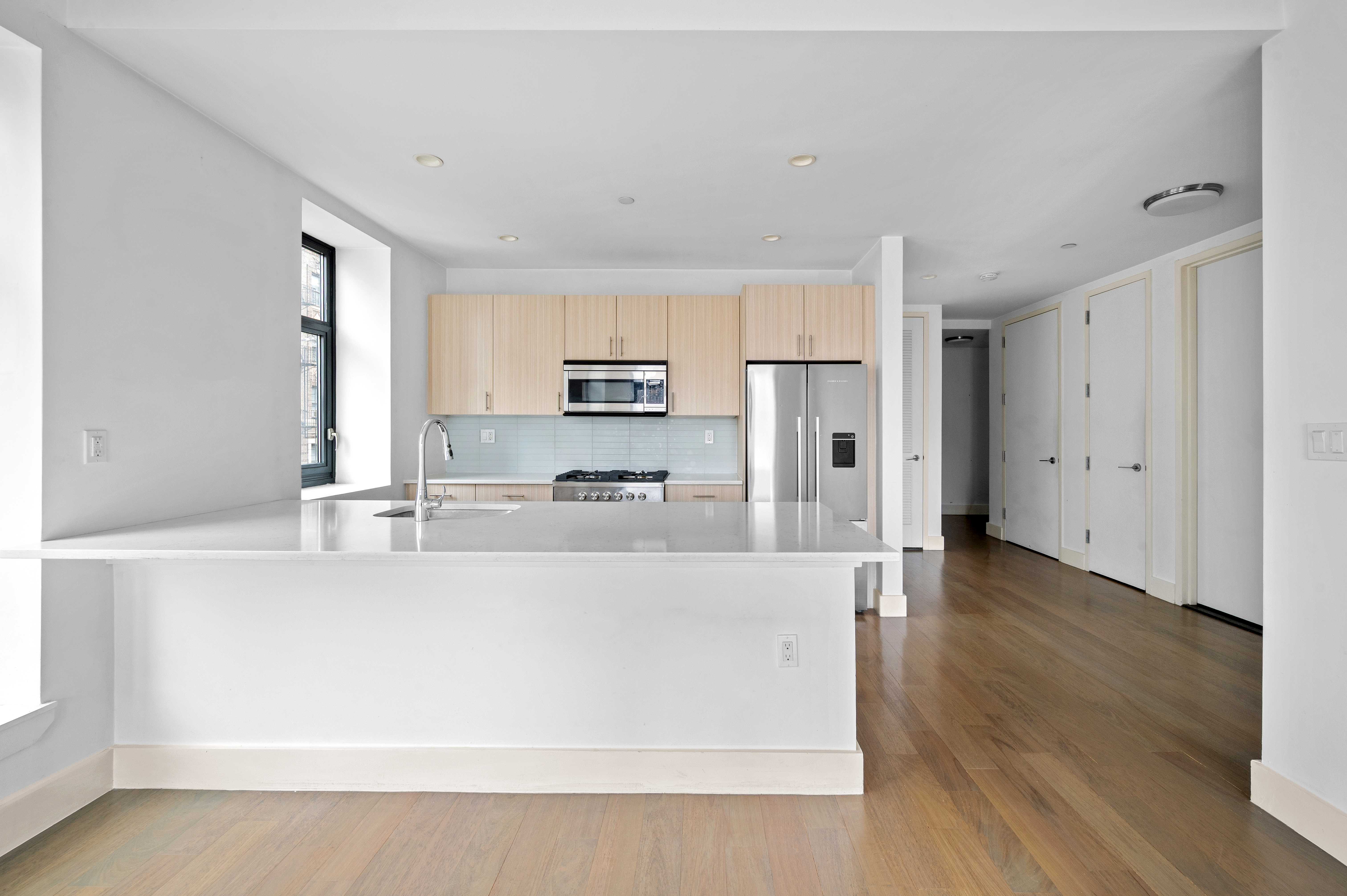 17 Convent Avenue Manhattan, NY 10027 - Photo 6 of 15 a large white kitchen with stainless steel appliances a large counter top and a stove