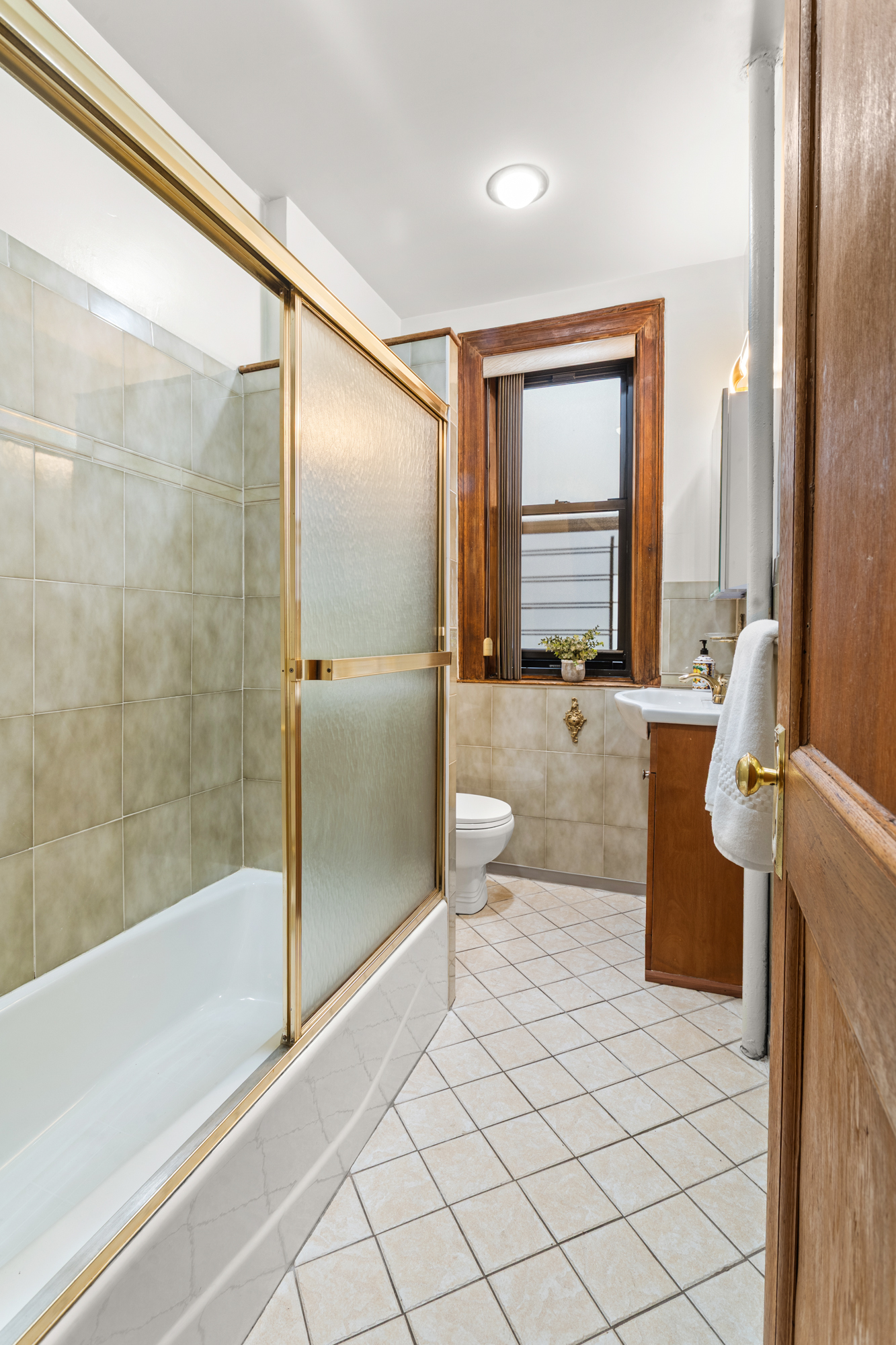 527 West 143rd Street, Unit 31 Manhattan, NY 10031 - Photo 17 of 29 a bathroom with a granite countertop sink a toilet and bathtub