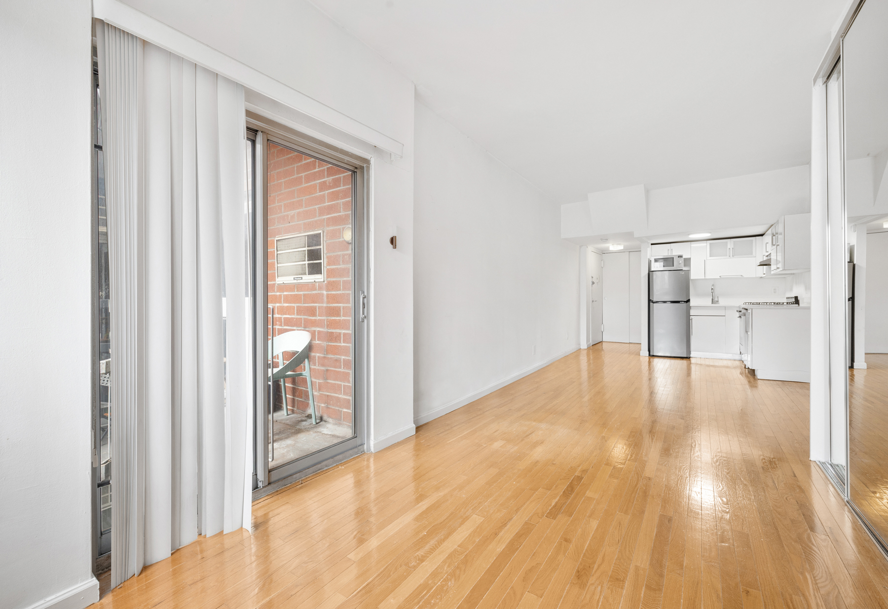 184 Thompson Street, Unit 4U Manhattan, NY 10012 - Photo 6 of 9 a view of empty room with wooden floor and floor to ceiling window