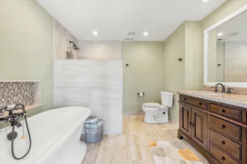 a spacious bathroom with a granite countertop sink a toilet and a tub