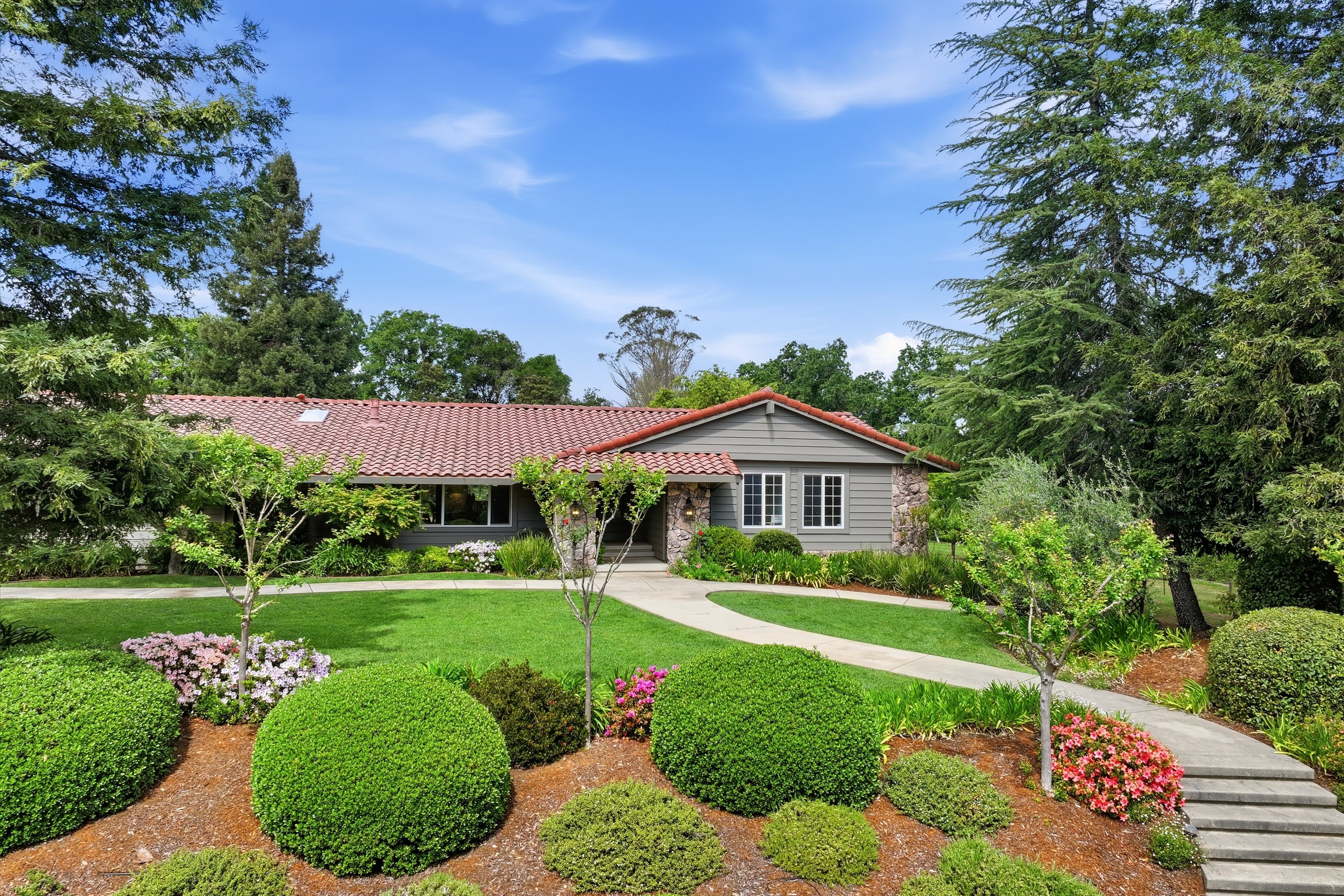 a front view of a house with a yard and potted plants