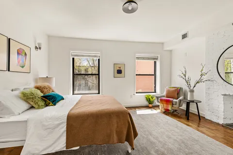 a bedroom with a bed a couch and dresser next to a window