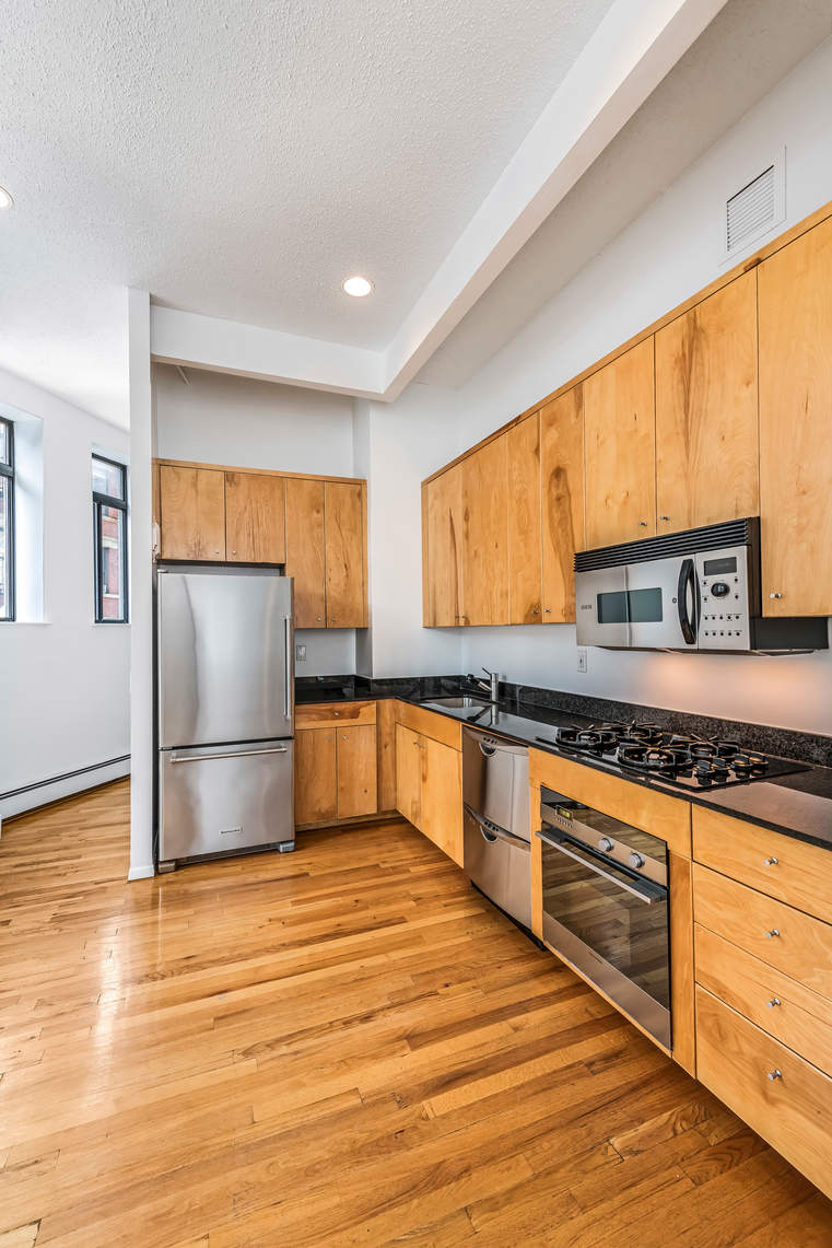 2 Cornelia Street, Unit 306 Manhattan, NY 10014 - Photo 8 of 13 a kitchen with stainless steel appliances granite countertop a refrigerator a sink dishwasher a stove and white countertops with wooden floor