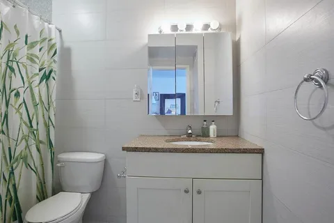 a bathroom with a granite countertop toilet sink and mirror